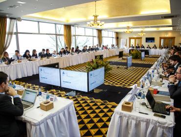 The image shows multiple participants sitting at a U-shaped table group